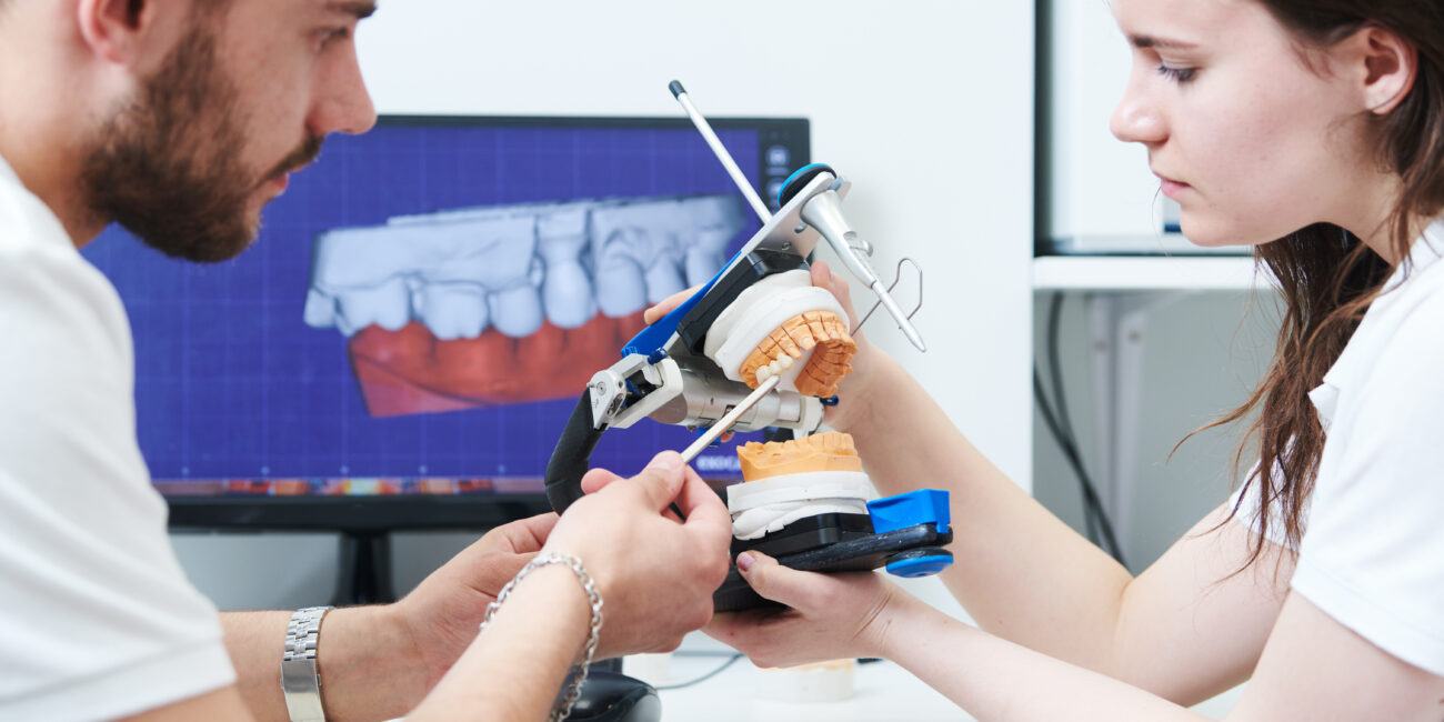 engineer and dentist technician discuss 3d teeth model in laboratory
